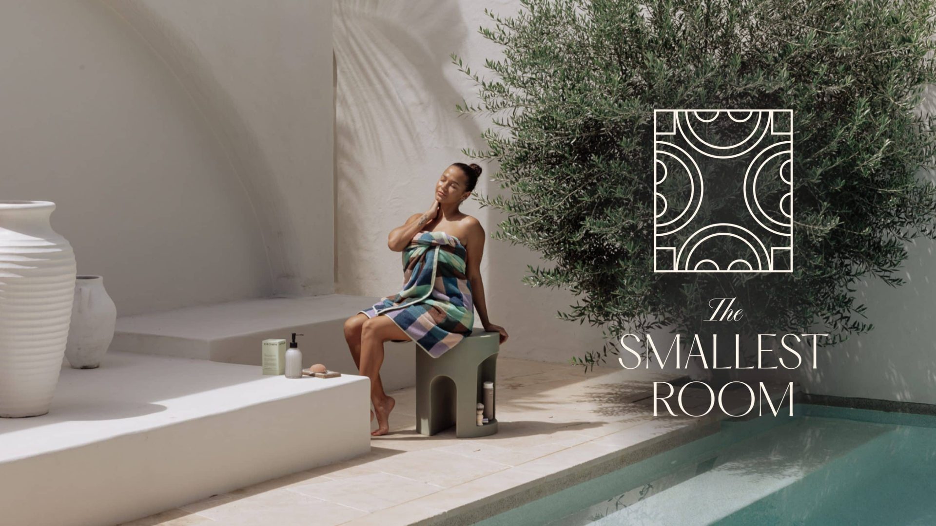 Woman sitting on a bathroom stool in a white mediterranean villa near a swimming pool