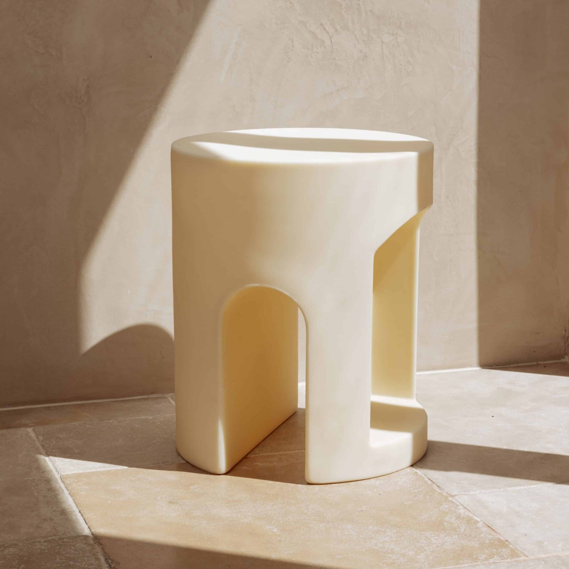 Ecommerce photography for a luxury bathroom stool by The Smallest Room sits on travertine tiles in morning sunlight